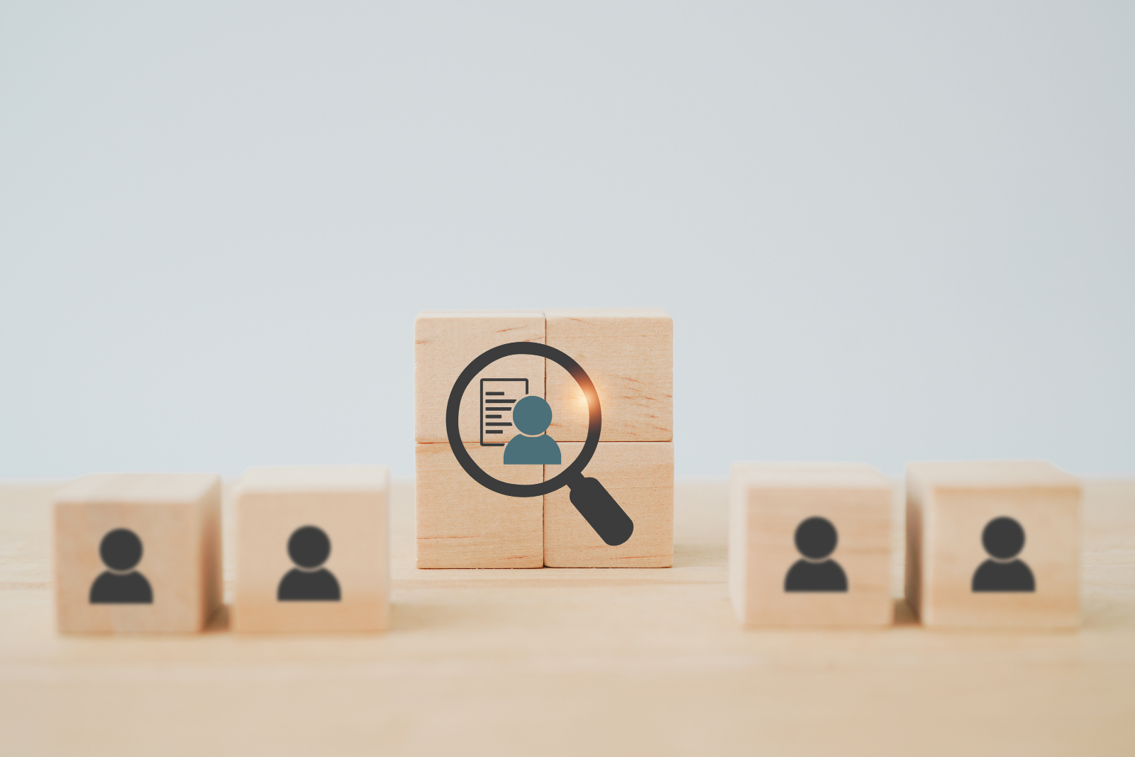 Wooden blocks with pictures of users on them with a magnifying glass in the center