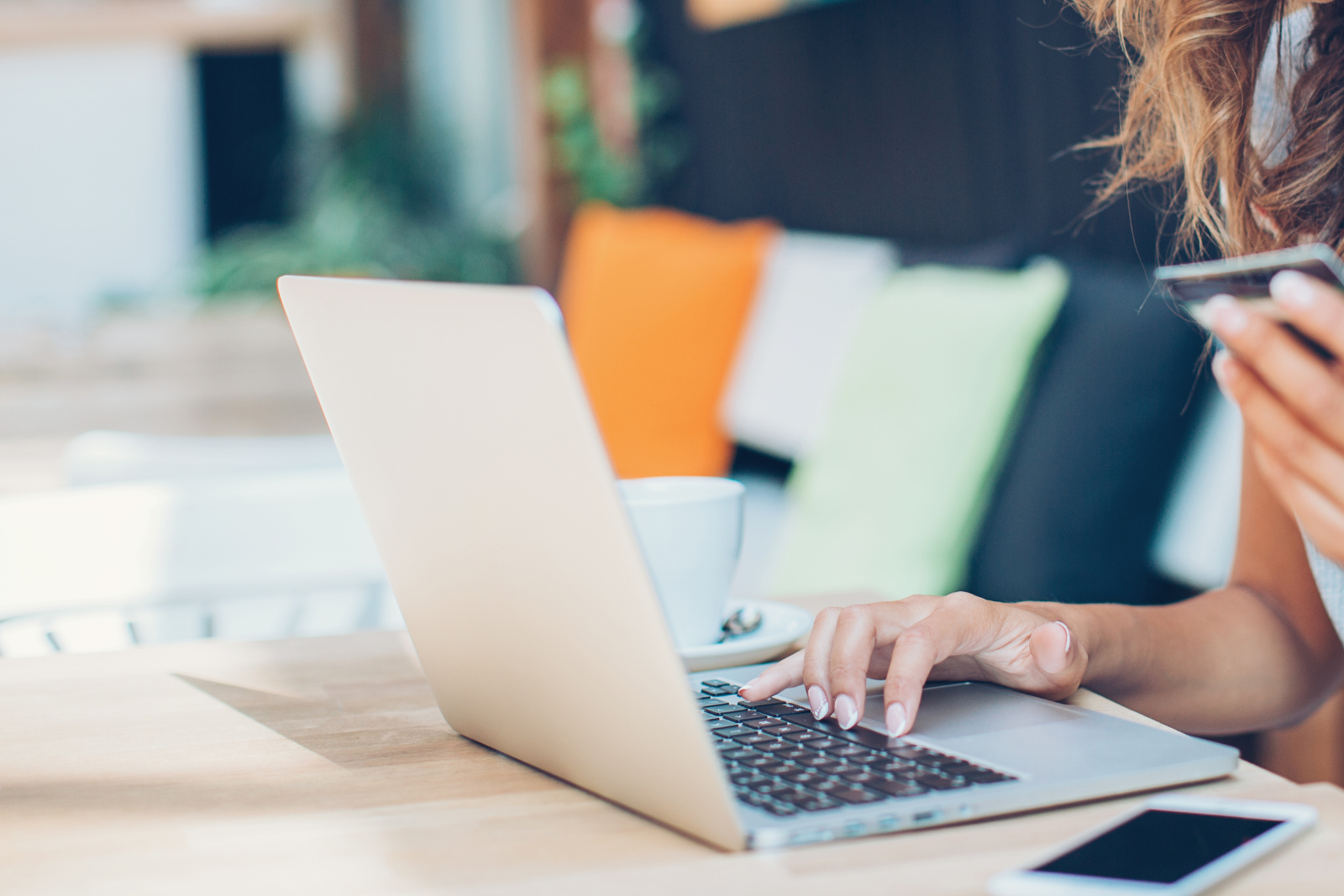 Woman typing on a laptop with a credit card in her hand