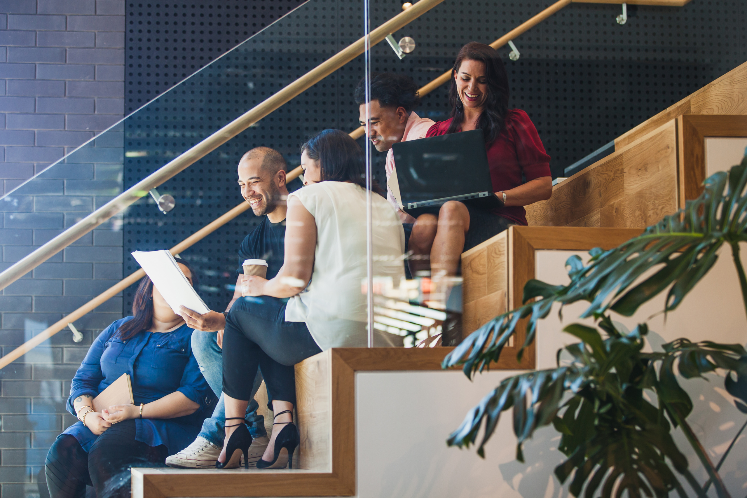 people sitting on steps working with laptops and smiling