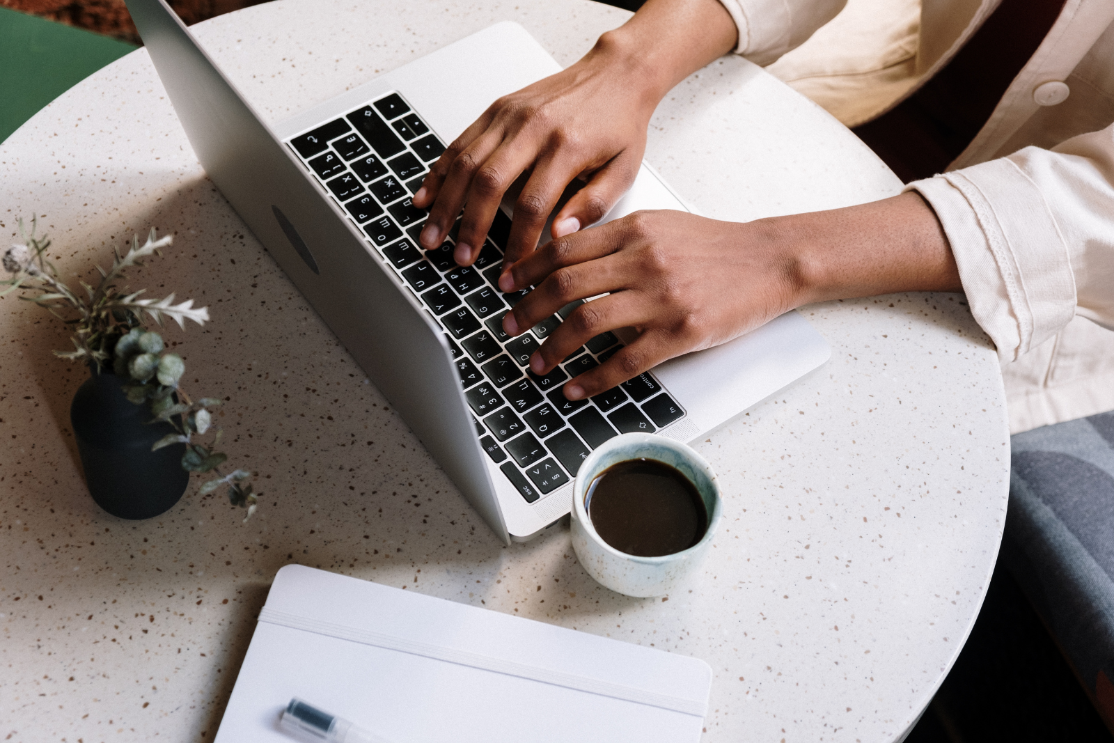 Woman typing on a computer with a coffee on her desk