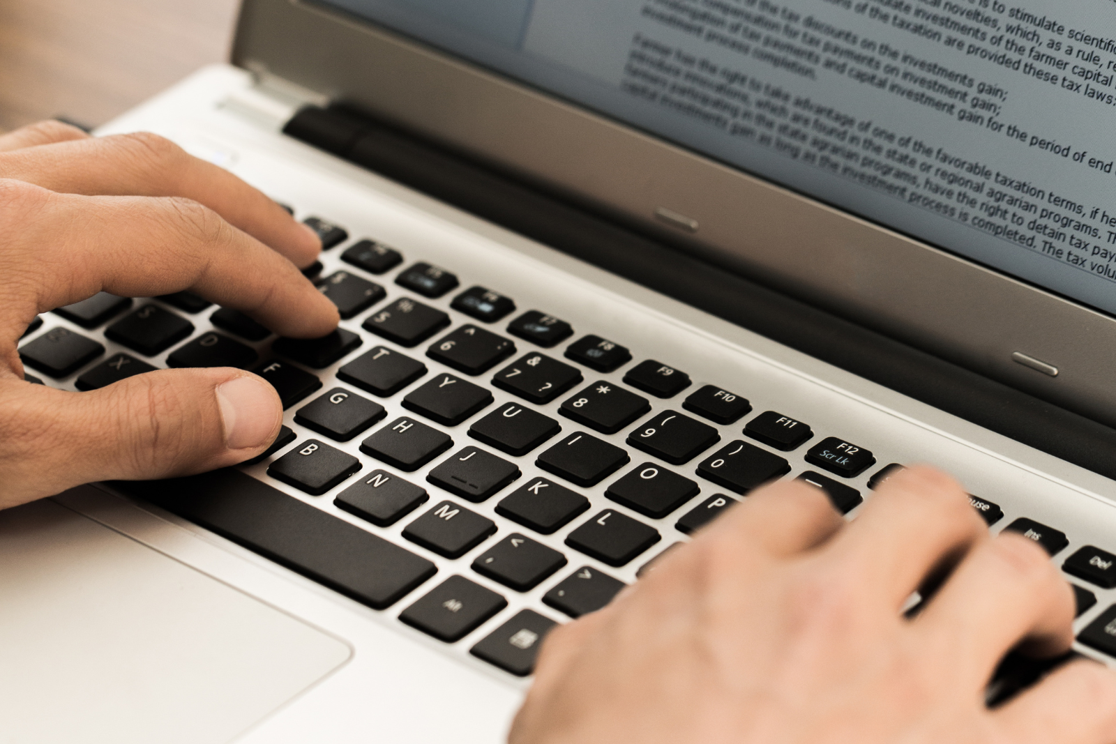 Person typing a word document on a laptio